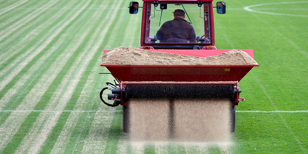 Sand-filled synthetic turf being infilled